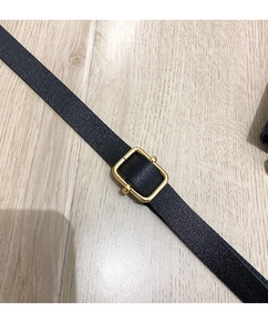Detail of black litchi texture leather strap with golden adjustable metal buckle