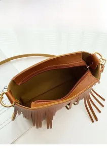 Dettaglio dell'ampio scomparto interno e della cerniera dorata della borsa marrone con frange