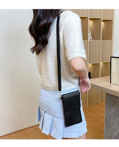 Close-up of black crossbody phone bag with hollowed-out texture and gold metal hooks