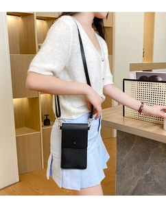 Detail of black pebbled leather touch screen phone bag with golden metal hardware