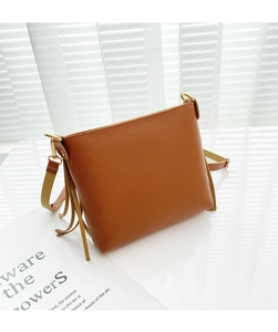 Dettaglio di una borsa a tracolla in pelle marrone con nappe laterali e tracolla beige