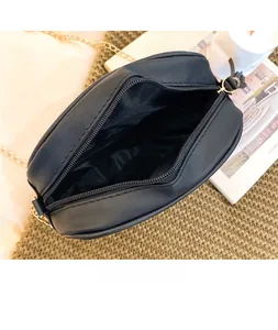 Internal view of black quilted crossbody bag with zipper and gold chain on beige fabric
