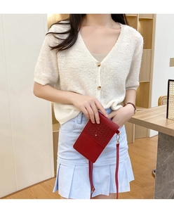 Detailed view of a red leather touch-screen phone bag with hollow-out design and strap