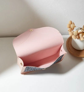 Détail d'un mini sac à bandoulière rose avec paillettes bleues et boucle dorée