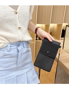 Detail of the laser-cut geometric pattern and metal clasp on this black crossbody phone bag