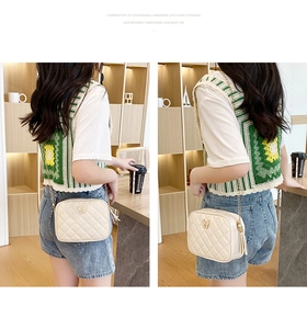 Quilted beige crossbody bag with butterfly clasp and tassel charm worn by a model