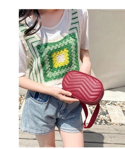 Detail of red quilted waist bag with V-shaped stitching and adjustable strap on a model