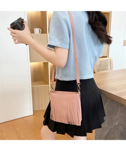 Borsa a tracolla rosa da donna con dettaglio frange indossata in uno stile casual