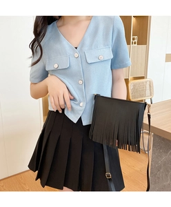 Dettaglio della borsa a tracolla nera con frange decorative su un outfit in stile coreano