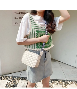 Detail of cream quilted crossbody bag with golden plaque and letter print strap