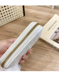Close-up of white quilted leather wallet featuring smooth golden zipper and elegant texture