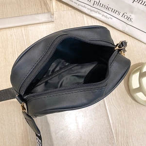 Minimalist black camera bag with wide lettered strap and spacious inner compartment