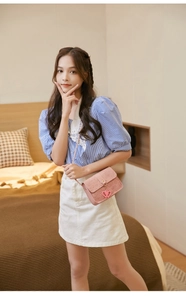 Detailed view of pink embossed crossbody bag with heart charms and cute cartoon patterns
