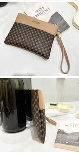 Detail view of the brown geometric pattern small handbag with beige wrist strap and zipper