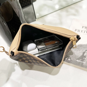 Retro patterned leather zipper pouch showing large interior capacity with cosmetics