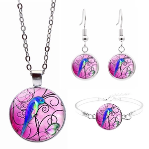 Nahaufnahme von Vogel- und Blumenmuster auf Glas-Cabochon Halskette, Ohrring und Armband