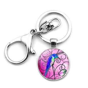 Detail of hummingbird glass pendant keychain with blue bird and pink butterfly illustration