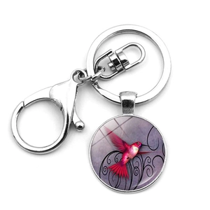 Macro detail of silver keychain with red hummingbird pendant and black scroll patterns