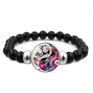 Close-up of black beaded bracelet with Yin Yang dragon pendant and cherry blossoms