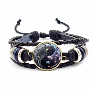 Détail d'un bracelet en cuir tissé avec dôme en verre Yin Yang galaxie et perles