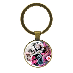 Detailed view of bronze keychain with glass cabochon featuring yin yang dragons and cherry blossoms
