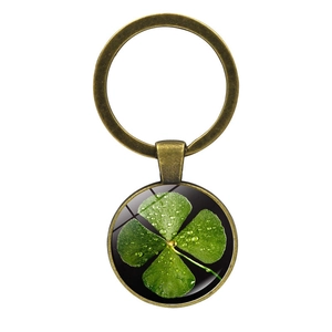 Close-up of a bronze four-leaf clover keychain with green leaf and dewdrop details