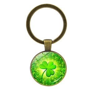 Detail of round bronze keychain featuring a green clover pattern under glass
