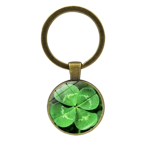 Close-up of vintage bronze keychain with four-leaf clover design under glass dome