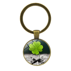 Macro detail of bronze four-leaf clover keychain with water droplets on glass pendant