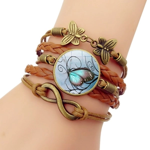 Detail eines mehrlagigen Lederarmbands mit Schmetterlingsanhängern und Unendlichkeitssymbol