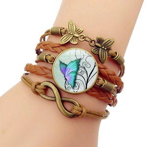 Detail eines Vintage-Lederarmbands mit Bronze-Schmetterling und Unendlichkeitssymbol