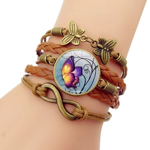 Detail eines Vintage Lederarmbands mit Schmetterling-Anhängern und Unendlichkeitssymbol