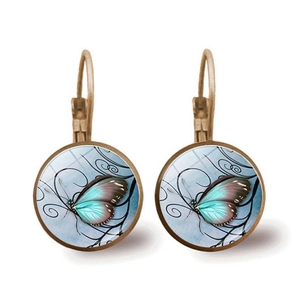 Detail view of retro bronze butterfly earrings with blue glass gem and floral vine patterns