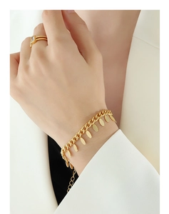 Detail of 18k gold plated chain bracelet with oval charms and square zircon ring