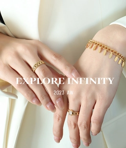 Detail of gold chain bracelet with oval metal charms and matching zircon rings on model