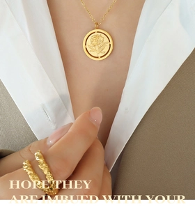 Détail du collier pendentif rose dorée et bague texturée portés par le mannequin