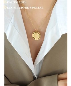 Gros plan du collier avec pendentif rose dorée porté sur une chemise blanche et un blazer