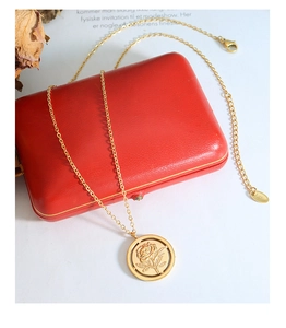 Détail du pendentif en relief rose vintage sur collier doré avec boîte à bijoux rouge