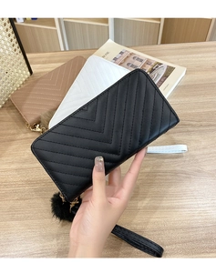 Detail of long quilted V-pattern clutch with wrist strap and pom-pom in multiple colors