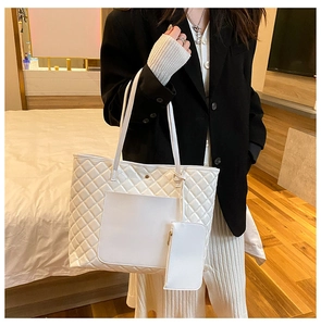 Macro detail of white quilted tote bag texture with removable pouch and golden metal hardware