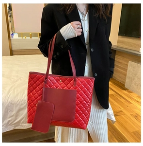 Red quilted tote bag and matching pouch set shown being carried in a cozy bedroom