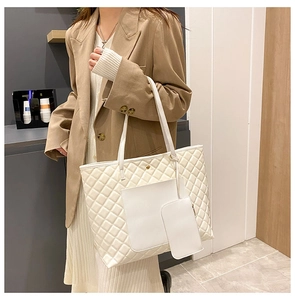 Close-up of white quilted tote bag with matching small coin purse and long shoulder strap
