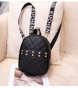 Détail du sac à dos matelassé noir avec clous dorés et bretelles ruban lettrées