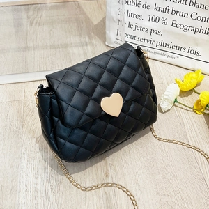Close-up of black quilted saddle bag with golden heart-shaped lock and chain strap