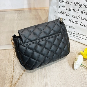 Close-up of black quilted small square bag with elegant gold chain strap on wood floor