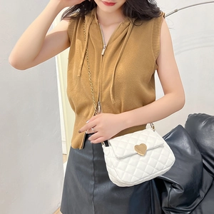 White quilted crossbody bag with gold heart clasp shown on a model in soft lighting