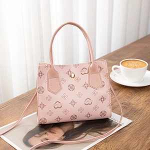 Pink printed leather tote bag with vintage patterns and gold hardware in a cozy cafe setting