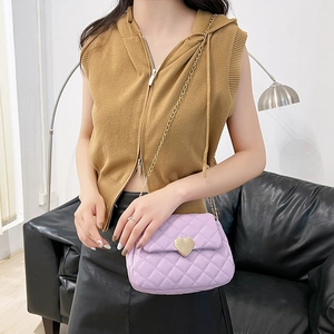 Detail of lavender quilted mini crossbody bag featuring a golden heart-shaped twist lock