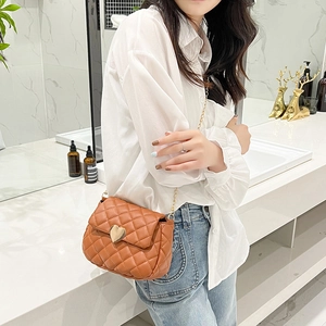 Caramel brown quilted crossbody bag with heart-shaped gold lock on a female model