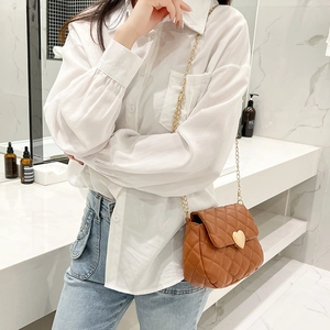 Detail of brown quilted crossbody bag with gold heart-shaped buckle and metal chain